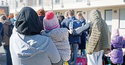 Geflüchtete aus der Ukraine stehen vor den Gebäuden einer Flüchtlingsunterkunft in Köln.