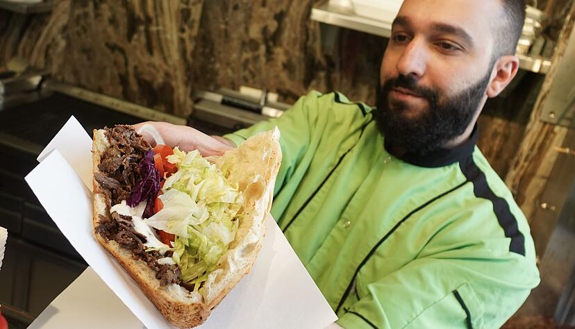 Ein Mitarbeiter eines Grill-Restaurants bereitet einen Döner zu.