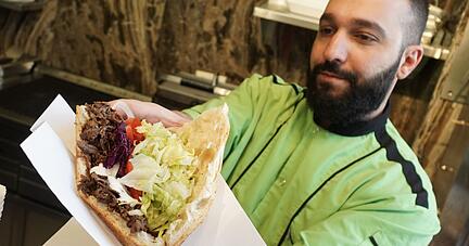 Ein Mitarbeiter eines Grill-Restaurants in Berlin bereitet einen Döner zu.