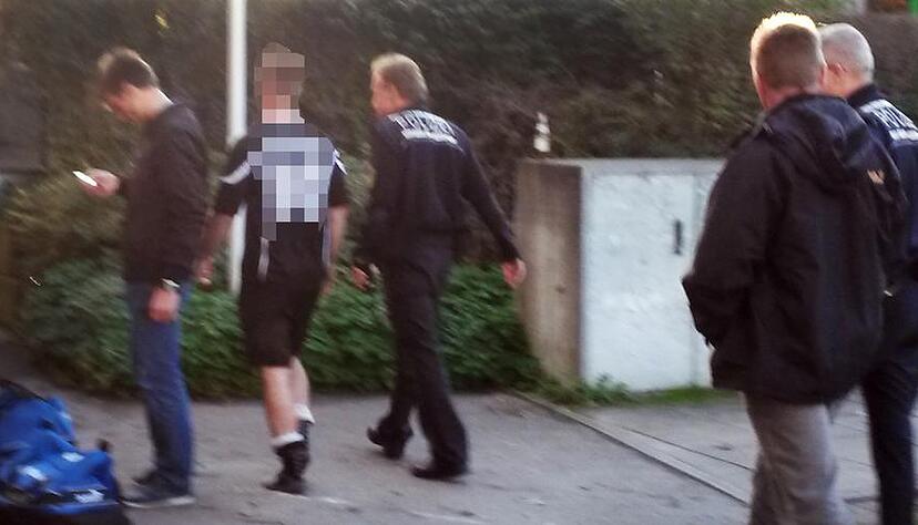 Polizisten begleiten den mutmaßlichen Schläger (2.v.l.) nach dem Spielabbruch vom Fußballplatz. Foto: privat