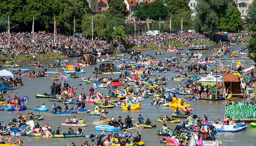 Unz&auml;hlige Schlauchboote treiben den Fluss hinab, w&auml;hrend noch mehr Schaulustige entlang des Ufers mitfeiern.