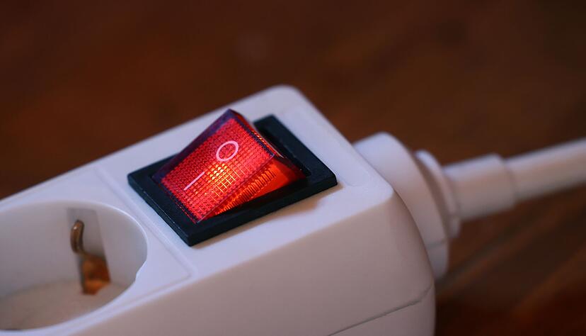 Der eingeschaltete Schutzschalter einer Mehrfachsteckdose leuchtet rot.