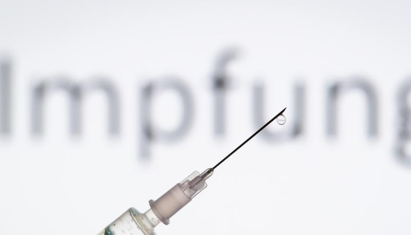 Eine Spritze wird vor den Schriftzug «Impfung» gehalten. Eine Spritze wird vor den Schriftzug «Impfung» gehalten.