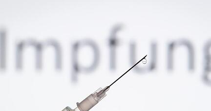 Eine Spritze wird vor den Schriftzug «Impfung» gehalten. Eine Spritze wird vor den Schriftzug «Impfung» gehalten.