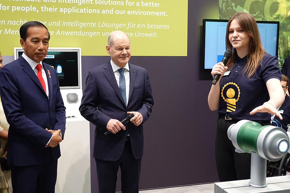 Bundeskanzler Olaf Scholz und Indonesiens Staatspr&auml;siedent Joko Widodo lassen sich von EBM-Papst-Studentin Melanie Bildhoff erl&auml;utern, was das Besondere an den Kompressoren ist.