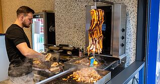 Ein Mitarbeiter schneidet in Karlsruhe das Brot für einen Oktopus-Döner auf.