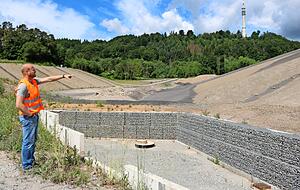 Deponieleiter Michael Freiberg zeigt auf die rechte Hangfl&auml;che, wo bis Ende Juni die Zwischenabdichtung zur alten Hausm&uuml;lldeponie komplettiert wird. Dort wird schwach belastetes Material entsorgt. In den linken Abschnitt kommt unbelasteter Abfall.