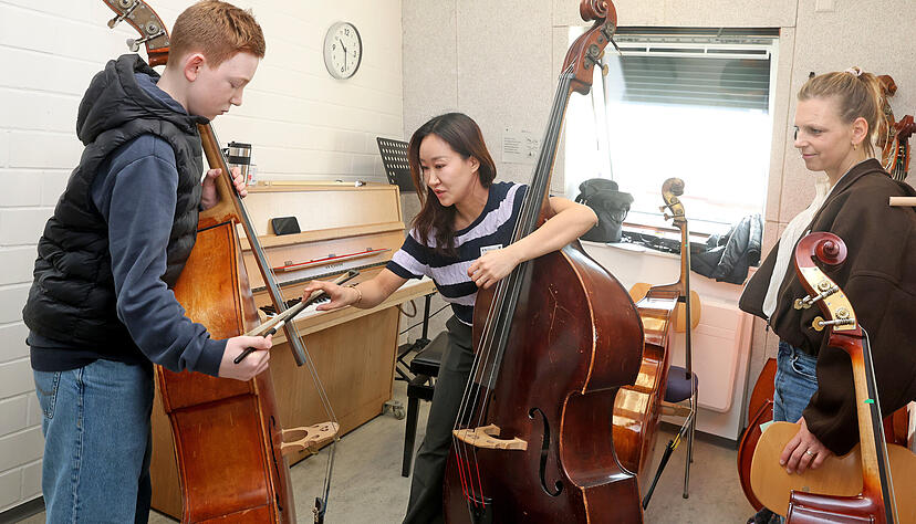 Musikschullehrerin Gayoung Lee (Mitte) zeigt dem zwölfjährigen Leo, wie ein Kontrabass gespielt wird. Leos Mutter Julie Gehrken schaut zu. Musikschullehrerin Gayoung Lee (Mitte) zeigt dem zwölfjährigen Leo, wie ein Kontrabass gespielt wird. Leos Mutter Julie Gehrken schaut zu.