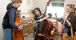 Musikschullehrerin Gayoung Lee (Mitte) zeigt dem zw&ouml;lfj&auml;hrigen Leo, wie ein Kontrabass gespielt wird. Leos Mutter Julie Gehrken schaut zu.
