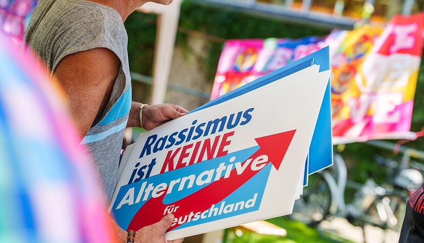 Eine Frau h&auml;lt bei einer Gegendemo ein&nbsp;Schild mit der Aufschrift &laquo;Rassismus ist keine Alternative&raquo; in den H&auml;nden.