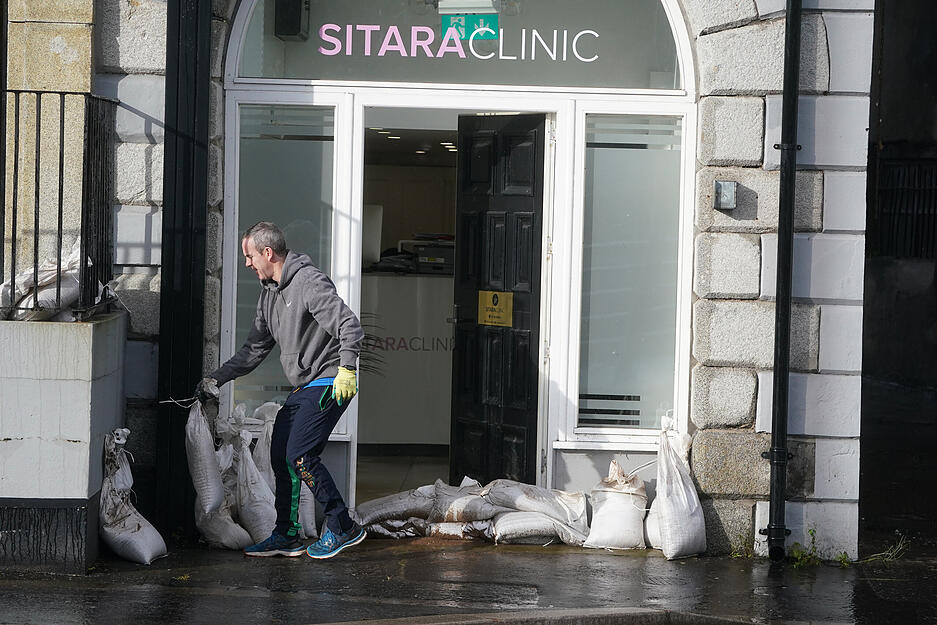 Merchants Quay, Großbritannien: Ein Mann platziert Sandsäcke vor einem Geschäft, nachdem der Kanal der Stadt bei heftigen Regenfällen über die Ufer getreten war.