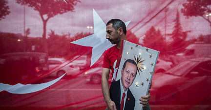 Ein Mann trägt ein Bild des türkischen Präsidenten Erdogan, während Anhänger nach der Verkündung der vorläufigen Wahlergebnisse vor dem Sitz der regierenden AKP-Partei jubeln. Foto: dpa