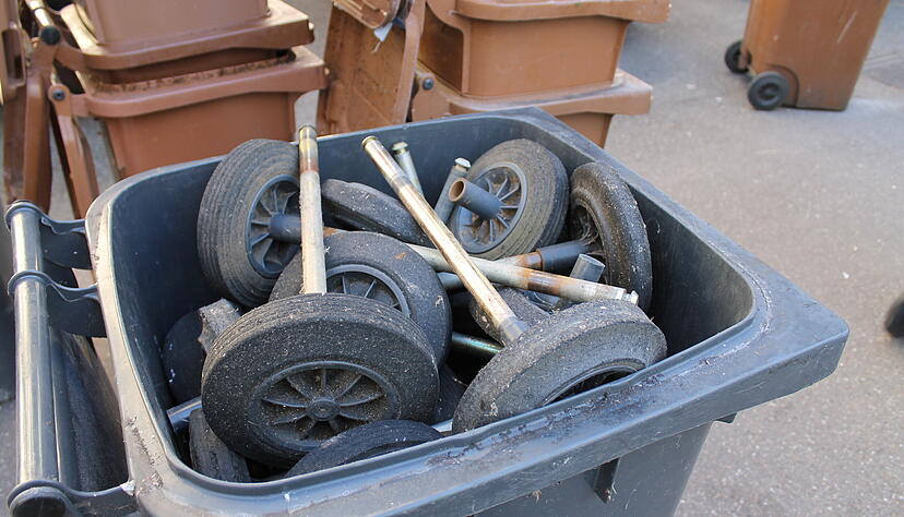 Das Abholteam montiert bei den M&uuml;lltonnen die Achsen mit den R&auml;dern ab, um die Beh&auml;lter platzsparend transportieren zu k&ouml;nnen.