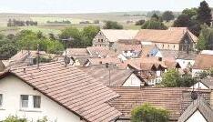 So sieht man Fürfeld selten: rechts das Schloss, links die Mühlwiesen (bei den mit roter Plane abgedeckten Containern). In der Mitte die große Fachwerkscheune, die abgebrochen werden soll.Foto: Steffan Maurhoff So sieht man Fürfeld selten: rechts das Schloss, links die Mühlwiesen (bei den mit roter Plane abgedeckten Containern). In der Mitte die große Fachwerkscheune, die abgebrochen werden soll.Foto: Steffan Maurhoff