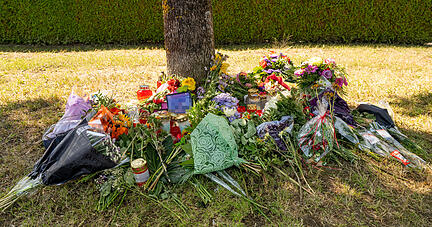 Blumen, Kerzen und Bilder liegen an einem Baum in der Nähe von Ingolstadt. In der Nähe war am 17. August 2022 eine weibliche Leiche in einem Pkw entdeckt worden.