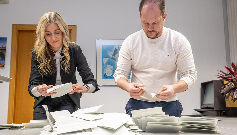 Die B&uuml;rgermeister-Assistentin Christina Fernandes und der K&auml;mmerer Christian Schneider entfalten die 509 in die Urne im Rathaus geworfenen Stimmscheine.