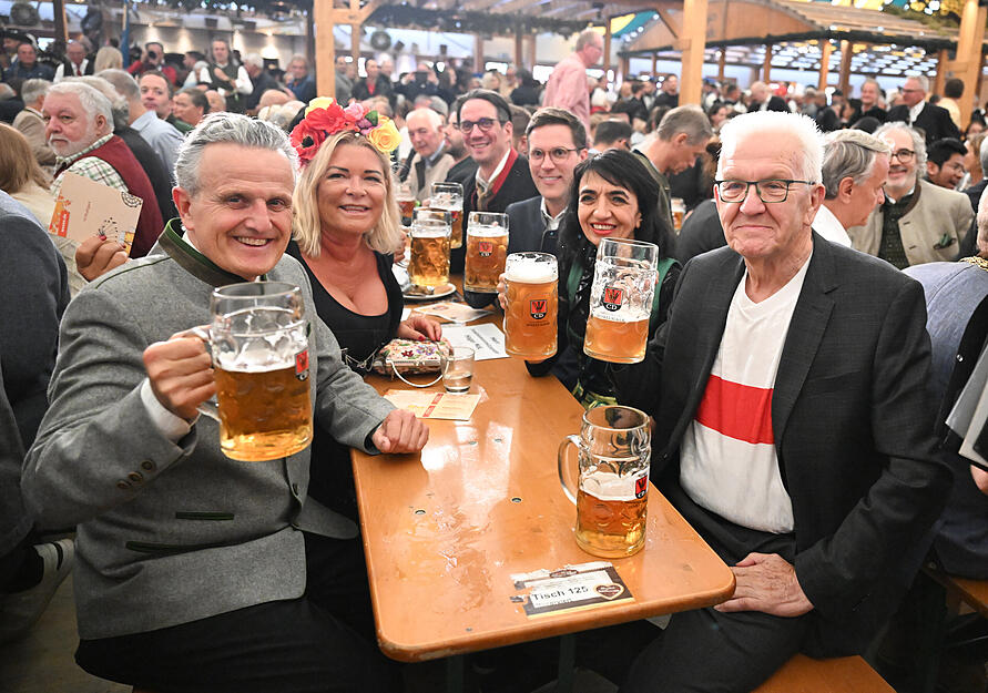 Frank Nopper (l, CDU), Oberbürgermeister der Stadt Stuttgart, Muhterem Aras (2.v.r, Bündnis 90/Die Grünen), Präsidentin des Landtags von Baden-Württemberg und Winfried Kretschmann (r, Bündnis 90/Die Grünen), Ministerpräsident von Baden-Württemberg, stoßen bei der Eröffnung des Cannstatter Volksfests mit Bierkrügen an.