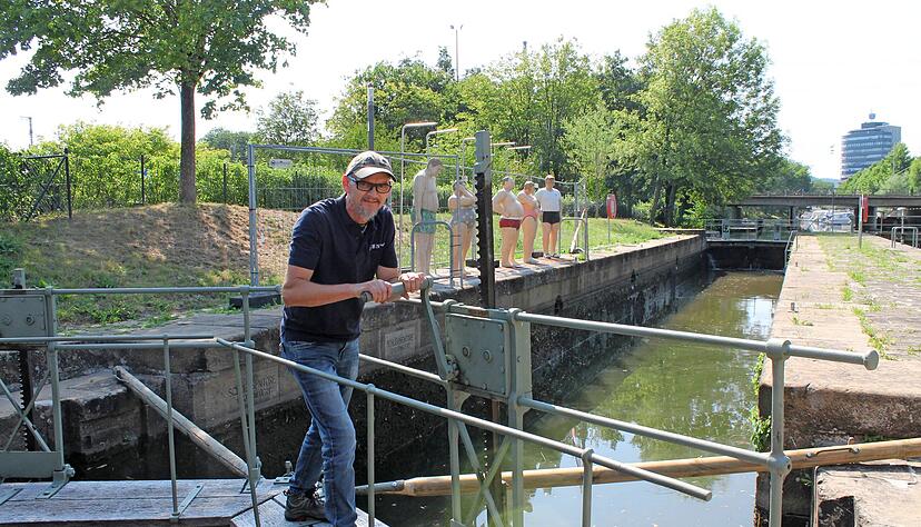 Fachmann Volker Schlägel demonstriert, wie Wasser aus der Schleusenkammer am Wilhelmskanal geleitet wird. Mit Holzstangen lassen sich die Tore öffnen. Foto: Hettich