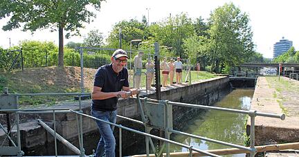 Fachmann Volker Schlägel demonstriert, wie Wasser aus der Schleusenkammer am Wilhelmskanal geleitet wird. Mit Holzstangen lassen sich die Tore öffnen.
Foto: Hettich