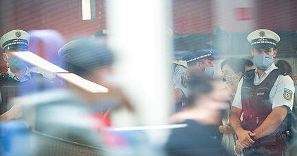 Polizeibeamte kontrollieren an einer Haltestelle im öffentlichen Nahverkehr die Einhaltung der Maskenpflicht. Foto: dpa