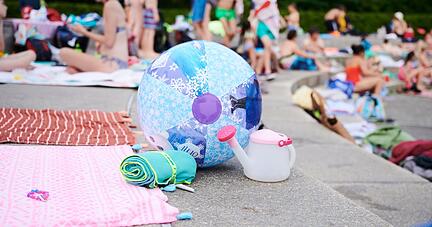 Ein Wasserball und Handt&uuml;cher liegen in einem Schwimmbad am Beckenrand.
