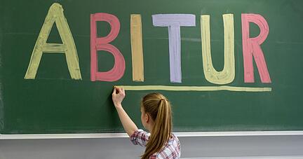 Eine Sch&uuml;lerin unterstreicht das Wort &laquo;Abitur&raquo; an einer Tafel.