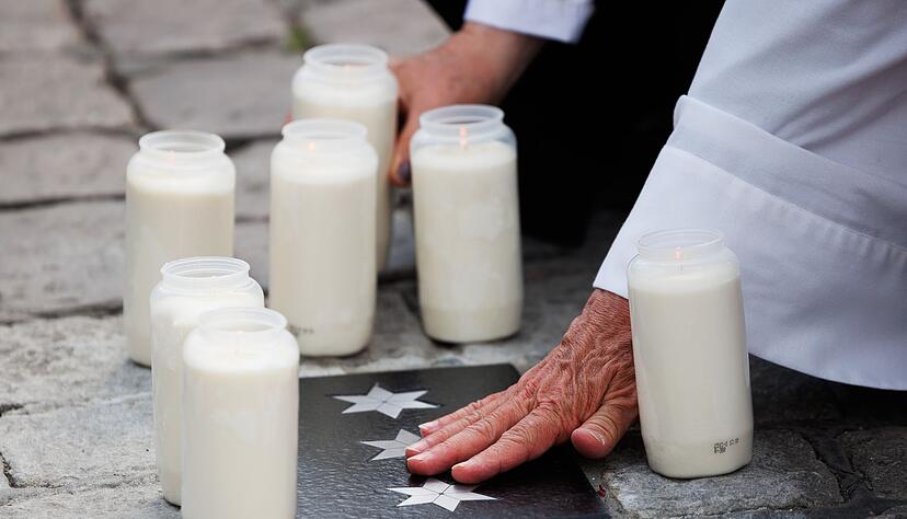 Personen ber&uuml;hren die Bodenplatte, die in Gedenken an Rouven Laur auf dem Marktplatz eingelassen wurde.