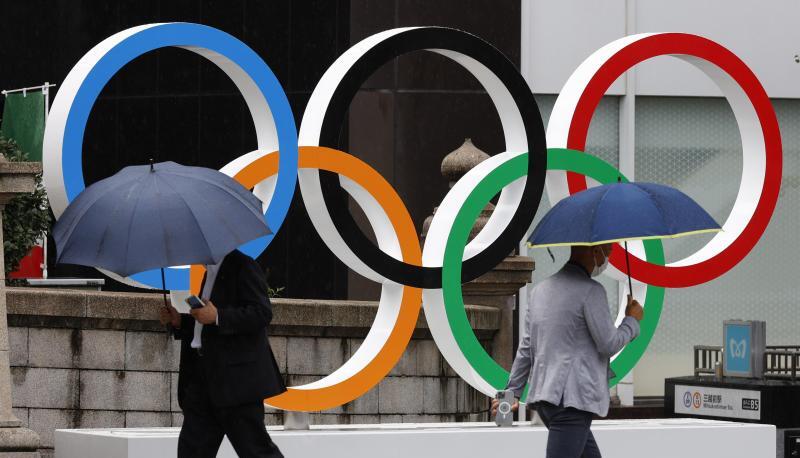 Passanten gehen an Olympischen Ringen in Tokio vorbei. Während der Spiele wird es keine Fans in den Stadien geben. Passanten gehen an Olympischen Ringen in Tokio vorbei. Während der Spiele wird es keine Fans in den Stadien geben.