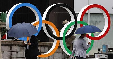 Passanten gehen an Olympischen Ringen in Tokio vorbei. Während der Spiele wird es keine Fans in den Stadien geben.