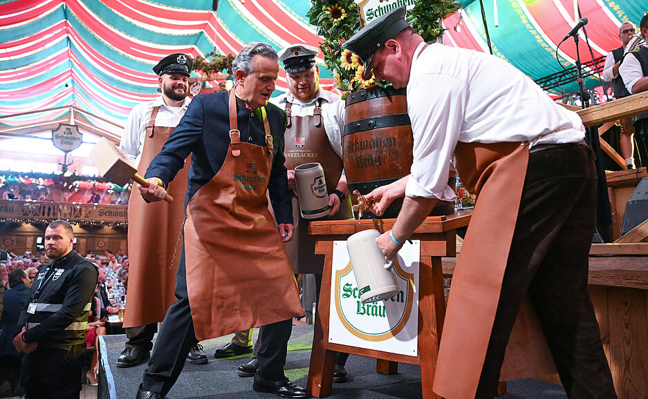 Frank Nopper (l, CDU), Oberbürgermeister von Stuttgart, sticht beim Stuttgarter Volksfest Cannstatter Wasen zur Eröffnung das erste Fass Bier an.