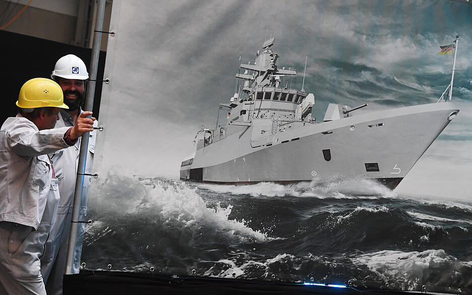 Werftarbeiter beobachten auf dem Werftgelände der zur Lürssen-Werftengruppe gehörenden Peene-Werft die Kiellegung einer Korvette einer neuen Serie der K130-Klasse für die Deutsche Marine.