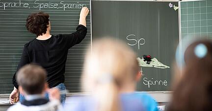 Eine Lehrerin schreibt in einer Schule an die Tafel.