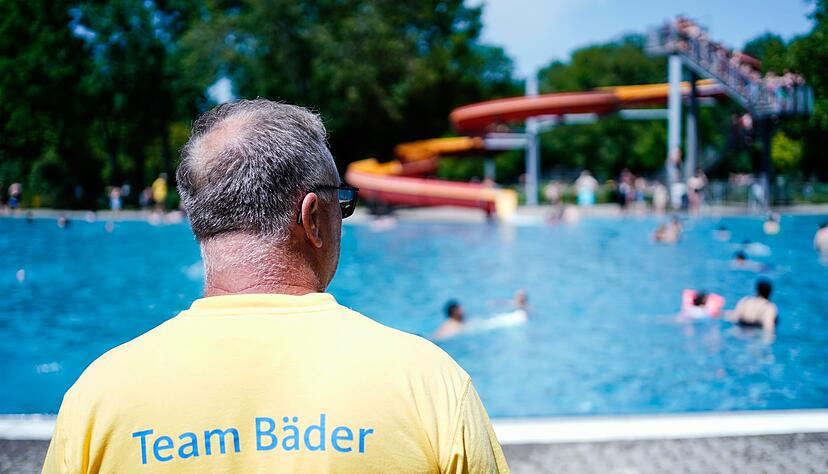 Ein Bademeister steht im Herzogenriedbad vor einem Schwimmbecken mit Wasserrutsche. Ein Bademeister steht im Herzogenriedbad vor einem Schwimmbecken mit Wasserrutsche.
