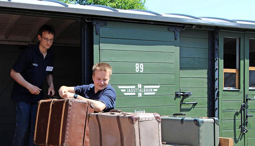 Aus dem frisch restaurierten Postwagen − ein Original der Jagsttalbahn − laden Ron Scherhaufer (vorne) und Stefan Haag symbolisch Gepäckstücke aus.
