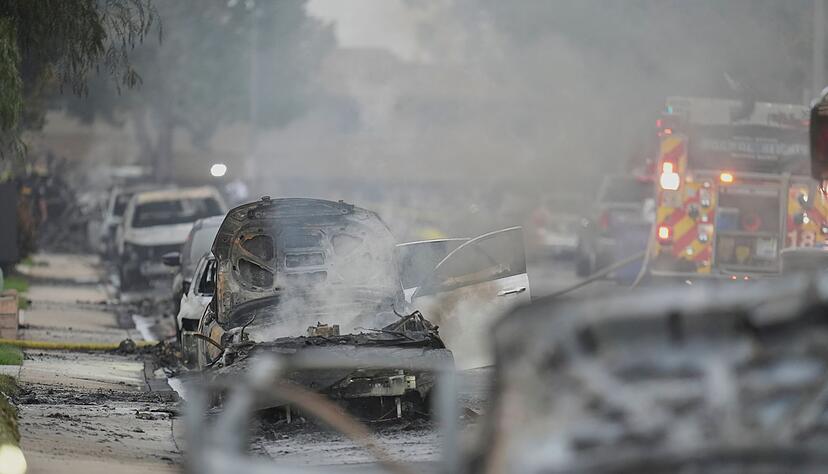 Einsatzkräfte fahren an beschädigten Fahrzeugen am Schauplatz des Absturzes eines Kleinflugzeugs in einem Stadtviertel von San Diego vorbei. Einsatzkräfte fahren an beschädigten Fahrzeugen am Schauplatz des Absturzes eines Kleinflugzeugs in einem Stadtviertel von San Diego vorbei.