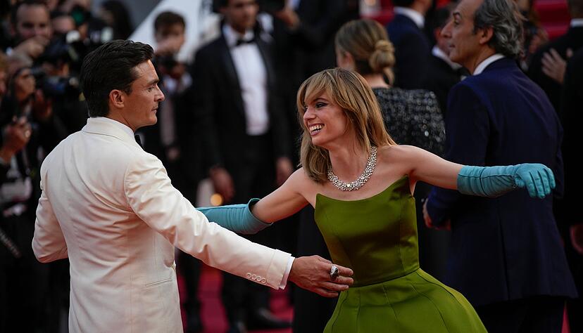 Rupert Friend und Maya Hawke tanzen auf dem roten Teppich.