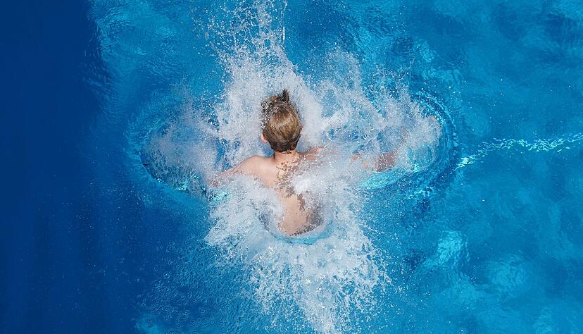 Ein Junge springt in einem Schwimmbad ins Wasser. Ein Junge springt in einem Schwimmbad ins Wasser.