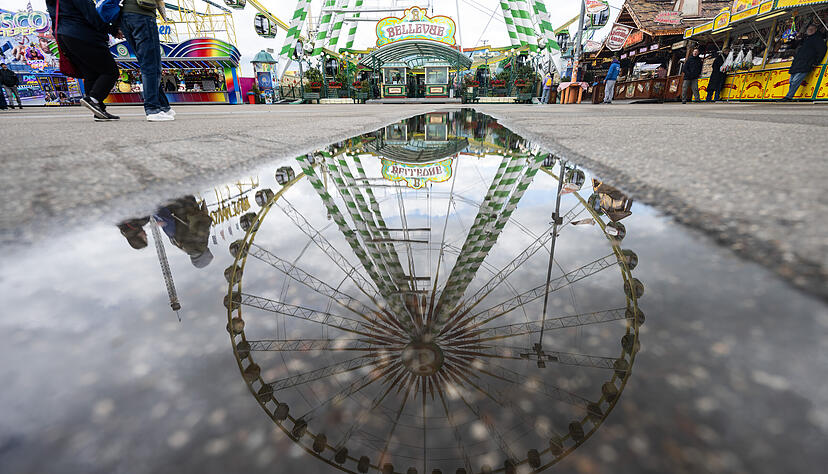 Ein Riesenrad spiegelt sich in einer Pfütze auf dem Festgelände. Das Wetter am ersten Festwochenende ist alles andere als frühlingshaft.