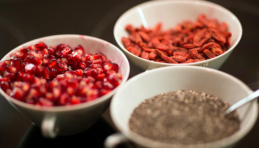 Chiasamen (unten rechts), getrocknete Gojibeeren und Granatapfelkerne (links) sind beliebte Superfood-Produkte. Foto: dpa