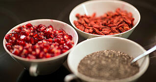 Chiasamen (unten rechts), getrocknete Gojibeeren und Granatapfelkerne (links) sind beliebte Superfood-Produkte. Foto: dpa
