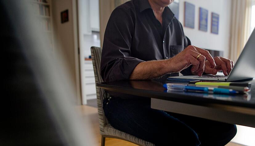 Ein Mann sitzt Zuhause am Esstisch und arbeitet.