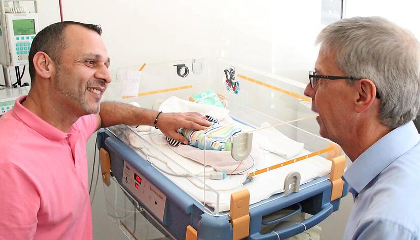 Zwillingsvater Robert Weissgerber sitzt am Bettchen seines kleinen Sohnes. Mit Klinikseelsorger J&uuml;rgen Rist spricht er &uuml;ber die vergangenen Wochen, die von H&ouml;hen und Tiefen gepr&auml;gt waren. 
Foto: SLK