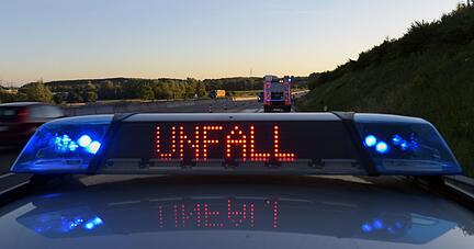 Ein Polizeifahrzeug warnt auf der Autobahn A8 eine Leuchtschrift vor einer Unfallstelle.