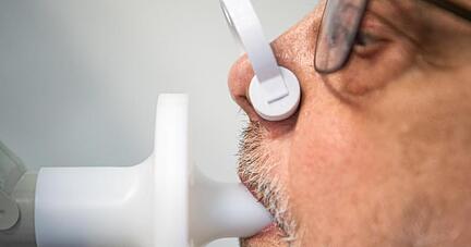 Ein Patient sitzt zur Überprüfung seiner Lungenfunktion in einem Bodyplethysmographen. Nach einer Covid-19-Erkrankung müssen viele Menschen mühsam wieder ins Leben finden.
