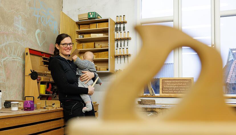 Johanna R&ouml;h steht mit ihrem Kind auf dem Arm in der Werkstatt ihres Betriebes. Die Mutter und Tischlermeisterin hat eine Petition zur Reform des Mutterschutzes auf den Weg gebracht.
