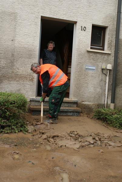 Schlamm wird vor einer Haustür in Ilsfeld weggeschippt.