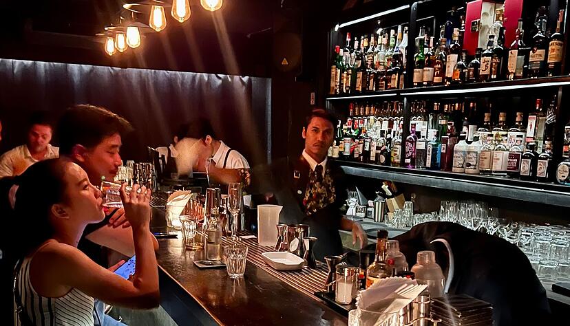 Gäste sitzen am Tresen einer Bar in Bangkok. Gäste sitzen am Tresen einer Bar in Bangkok.