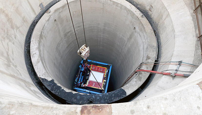 In einem soliden Gestell aus blauen Stahlträgern wird das Feuerwehrauto am Schacht Konradsberg in das Salzbergwerk Heilbronn hinabgelassen.