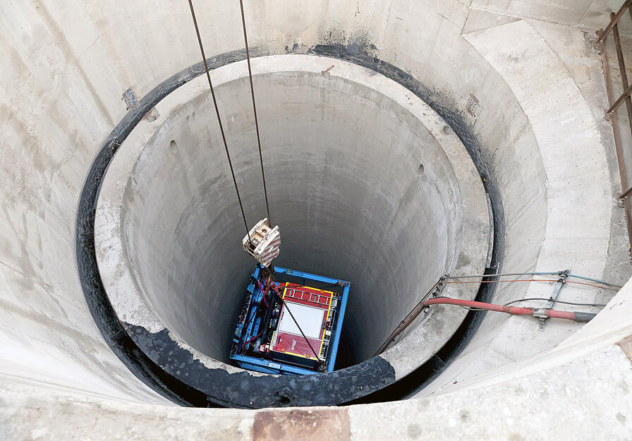 In einem soliden Gestell aus blauen Stahlträgern wird das Feuerwehrauto am Schacht Konradsberg in das Salzbergwerk Heilbronn hinabgelassen.