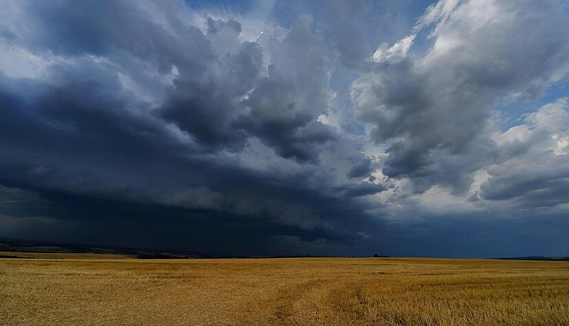 Dunkle Wolken ziehen über ein Feld. Nach den Sommertemperaturen sind ab Donnerstag in Baden-Württemberg Gewitter möglich. Foto: Archiv/dpa
